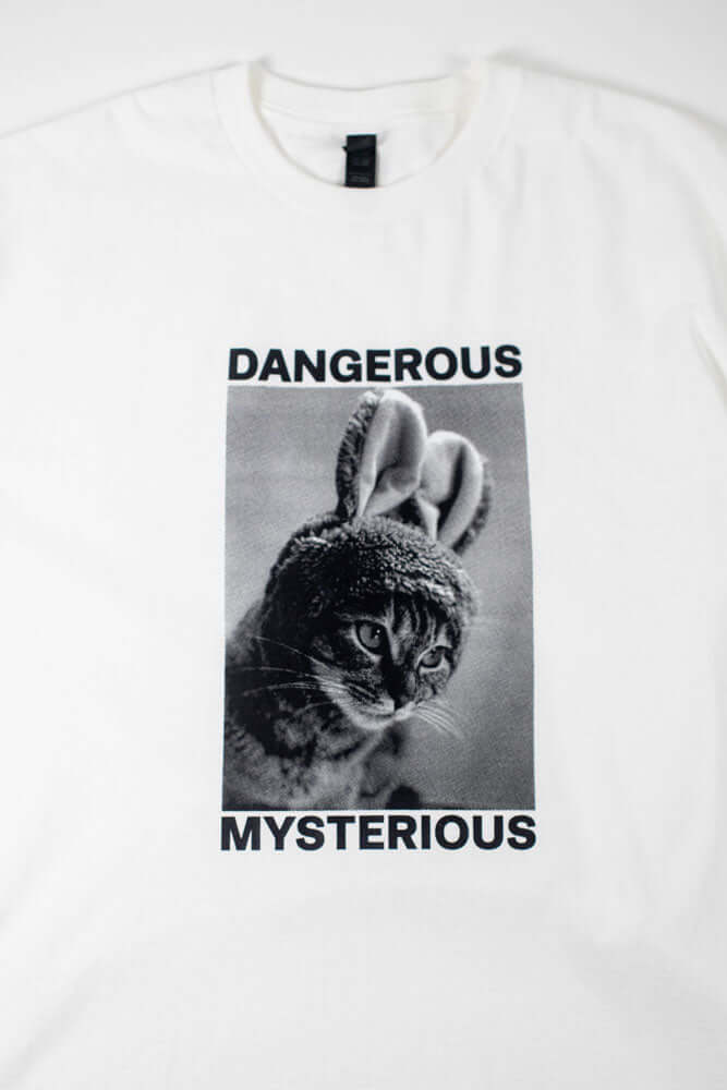 White t-shirt with a cat in bunny ear that reads DANGEROUS MYSTERIOUS